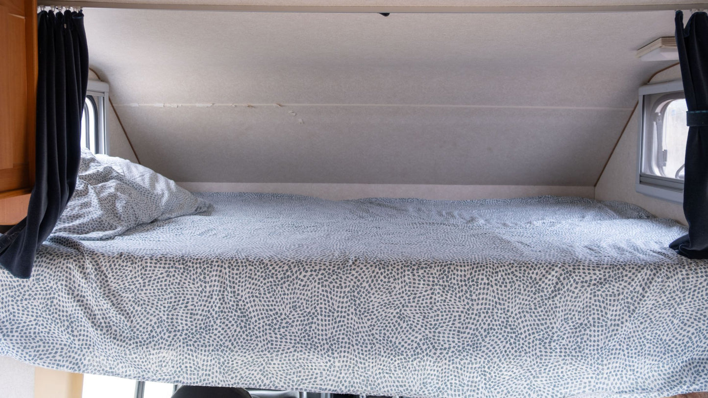 Bunk bed in a compact living space with curtains on either side.