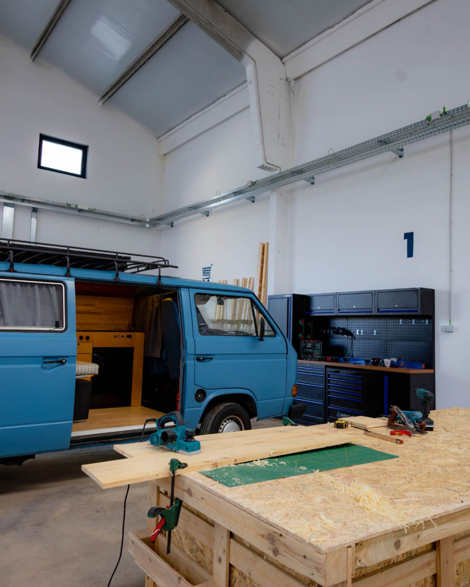 Spacious van conversion workshop in Porto with workbenches, power tools, and storage shelves