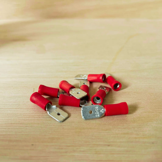 Red 1.5mm² electrical connector for campervan 12V wiring, crimped onto a copper wire with pliers for secure power connections.
